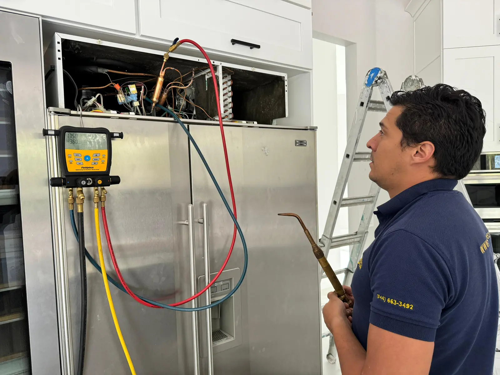 Quality Repairs technician checking refrigerant pressures on a built-in refrigerator