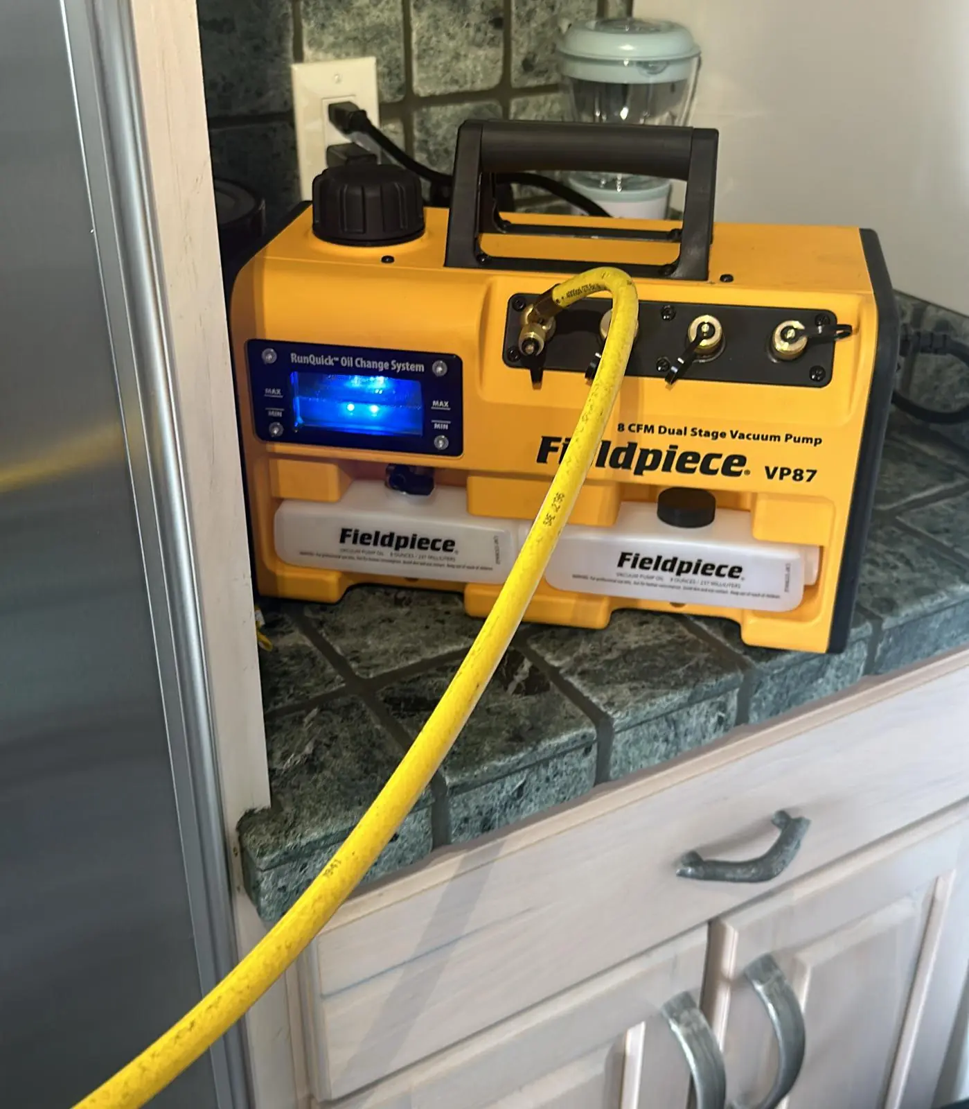 Vacuum pump evacuating a refrigeration system on a kitchen counter